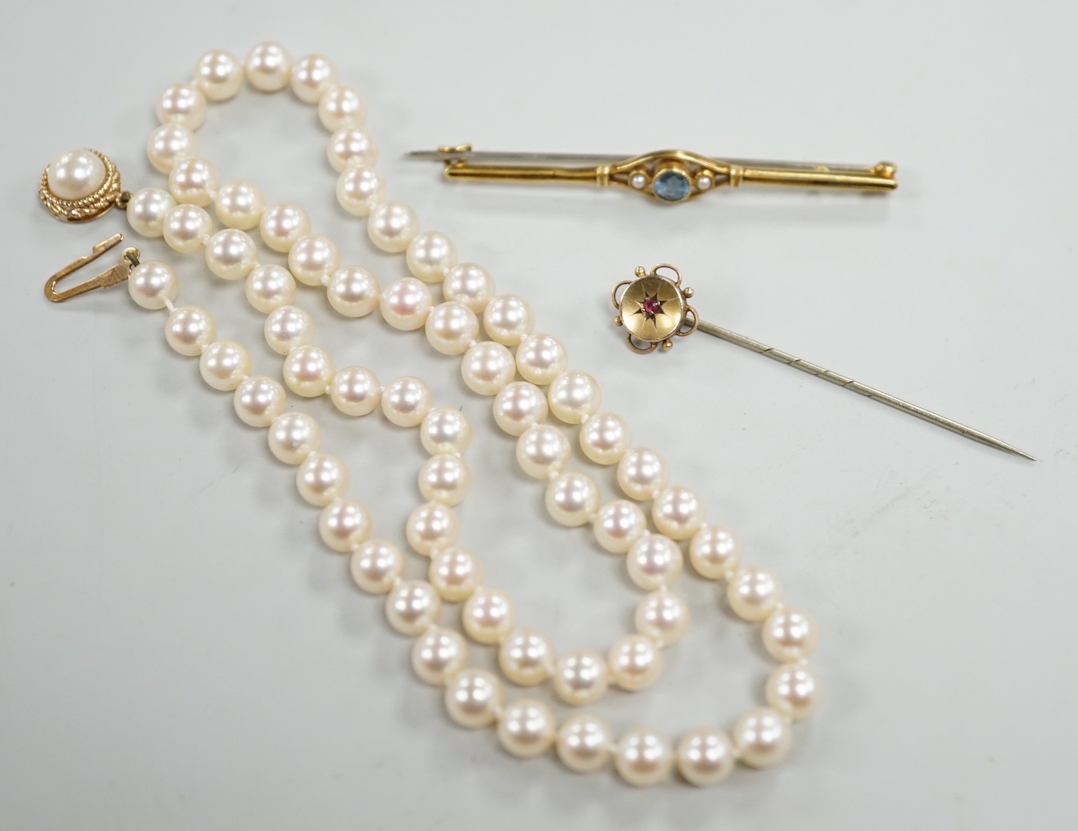 A single strand cultured pearl necklace, with 9ct gold clasp, 46cm, together with a yellow metal and ruby stick pin and a similar gem set bar brooch.